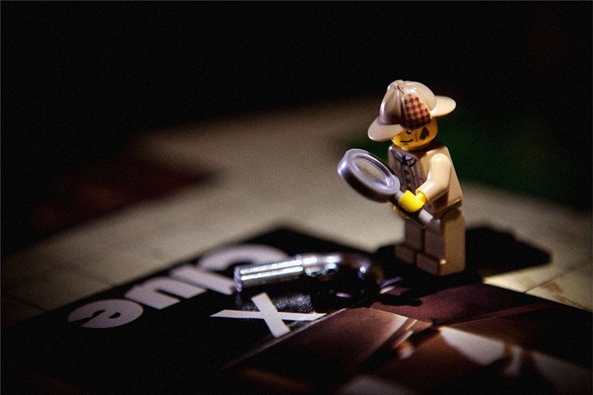 Photo of a Lego minifigure detective standing on a Clue game board