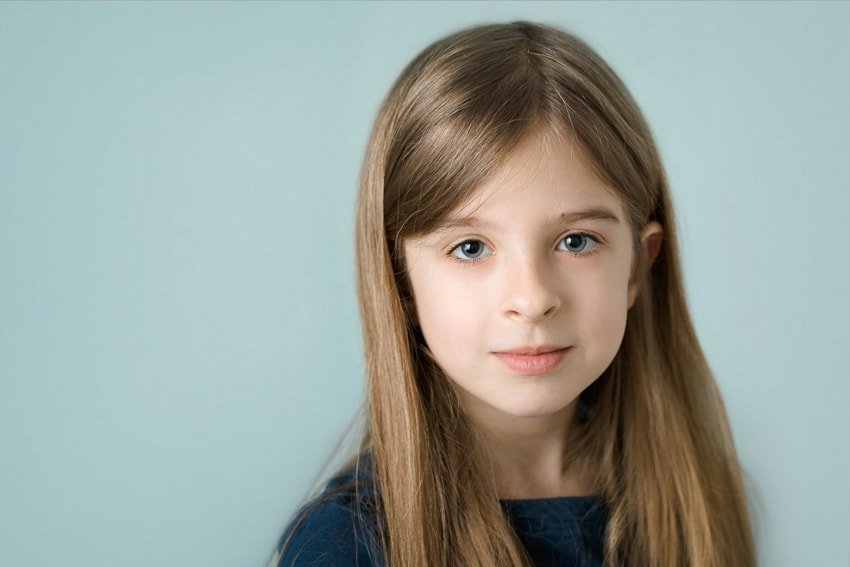 Head and shoulders photo of a little girl against a pale gray blue background